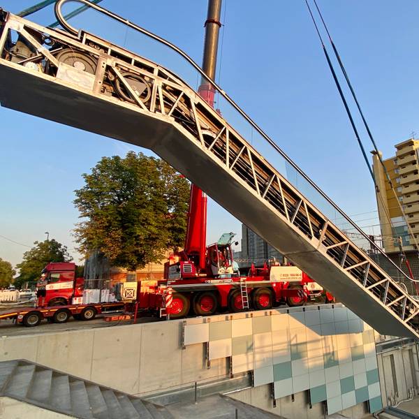 Eine Rolltreppe wird an einem Kran in eine Unterführung gehoben.
