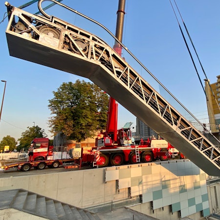 Eine Rolltreppe wird an einem Kran in eine Unterführung gehoben.