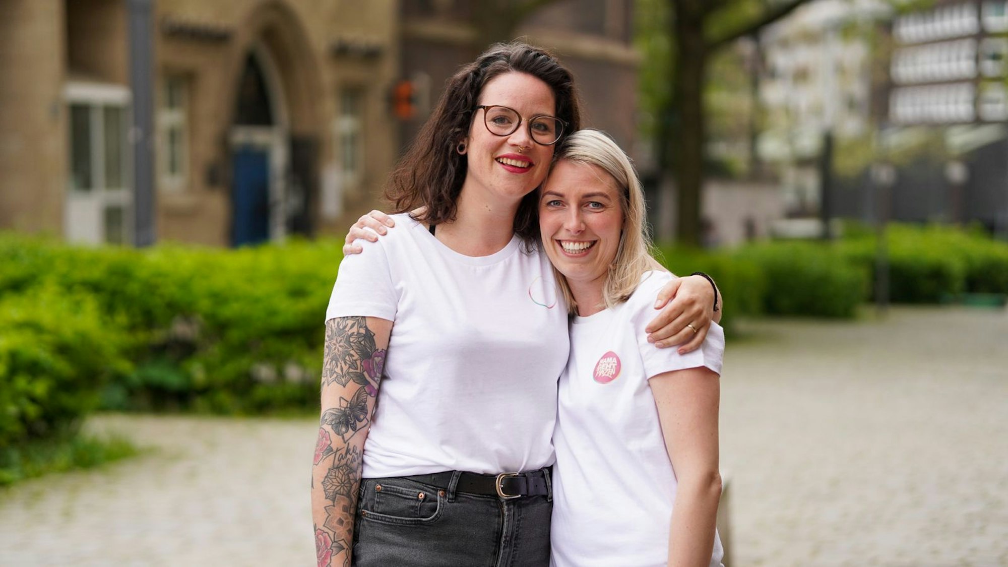 Zwei Frauen stehen Arm in Arm nebeneinander.
