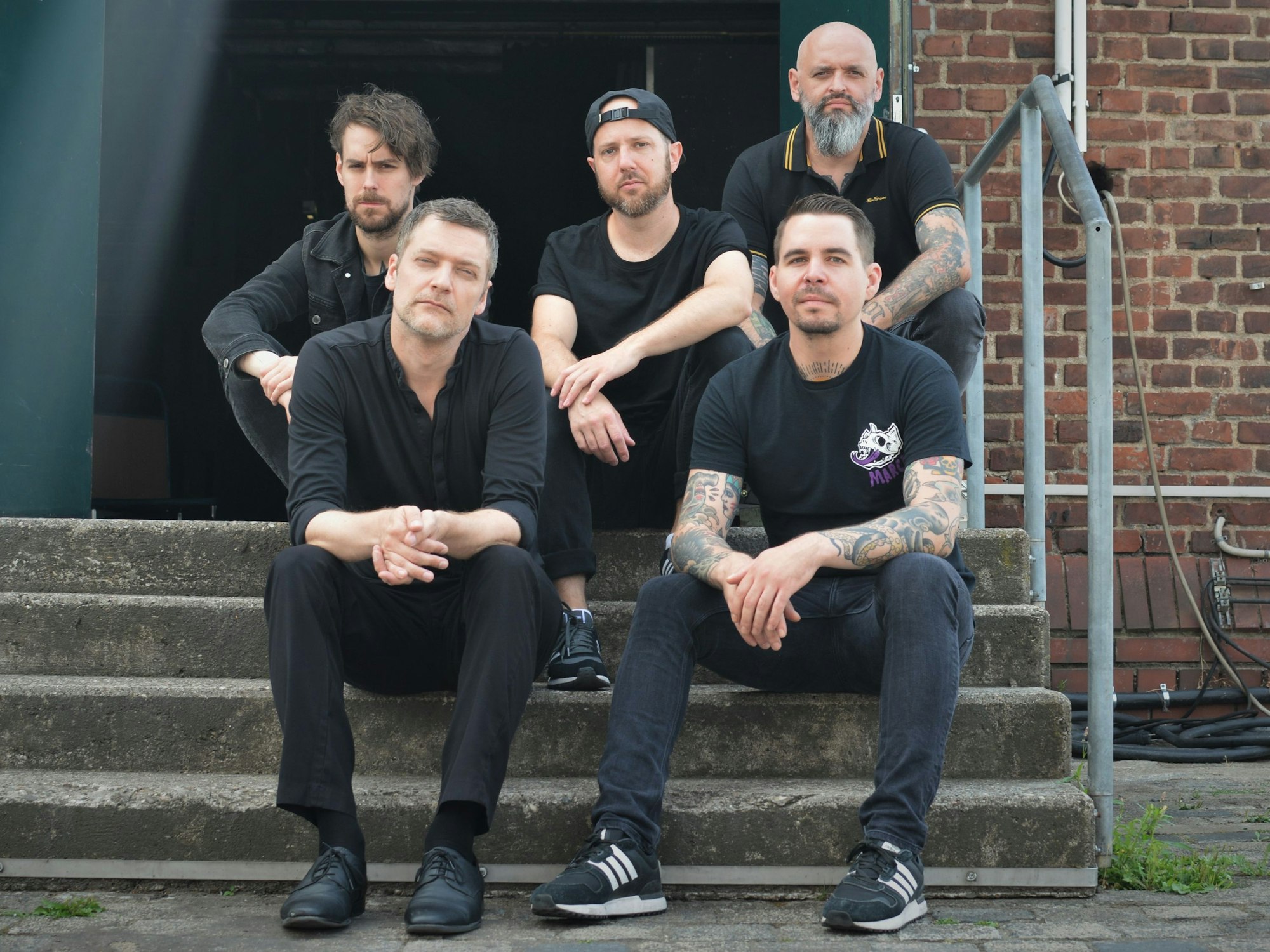 Die Band sitzt auf einer Treppe vor dem E-Werk.