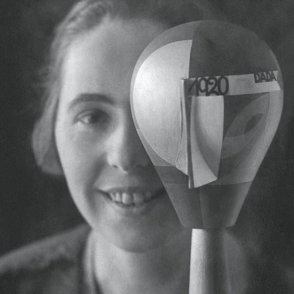 Sophie Taeuber-Arp schaut in dei Kamera, ein Auge wird von einem beklebten Puppenkopf verdeckt.