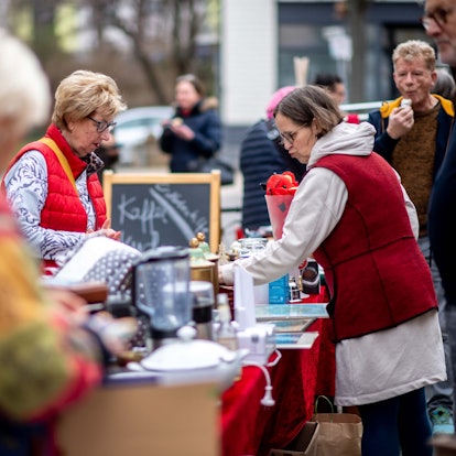 Das Bild zeigt einige Besucher des Trödelmarkts. Sie stöbern durch die angebotenen Artikel.