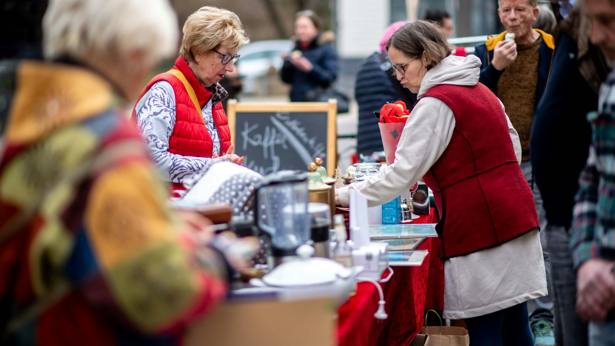 Das Bild zeigt einige Besucher des Trödelmarkts. Sie stöbern durch die angebotenen Artikel.