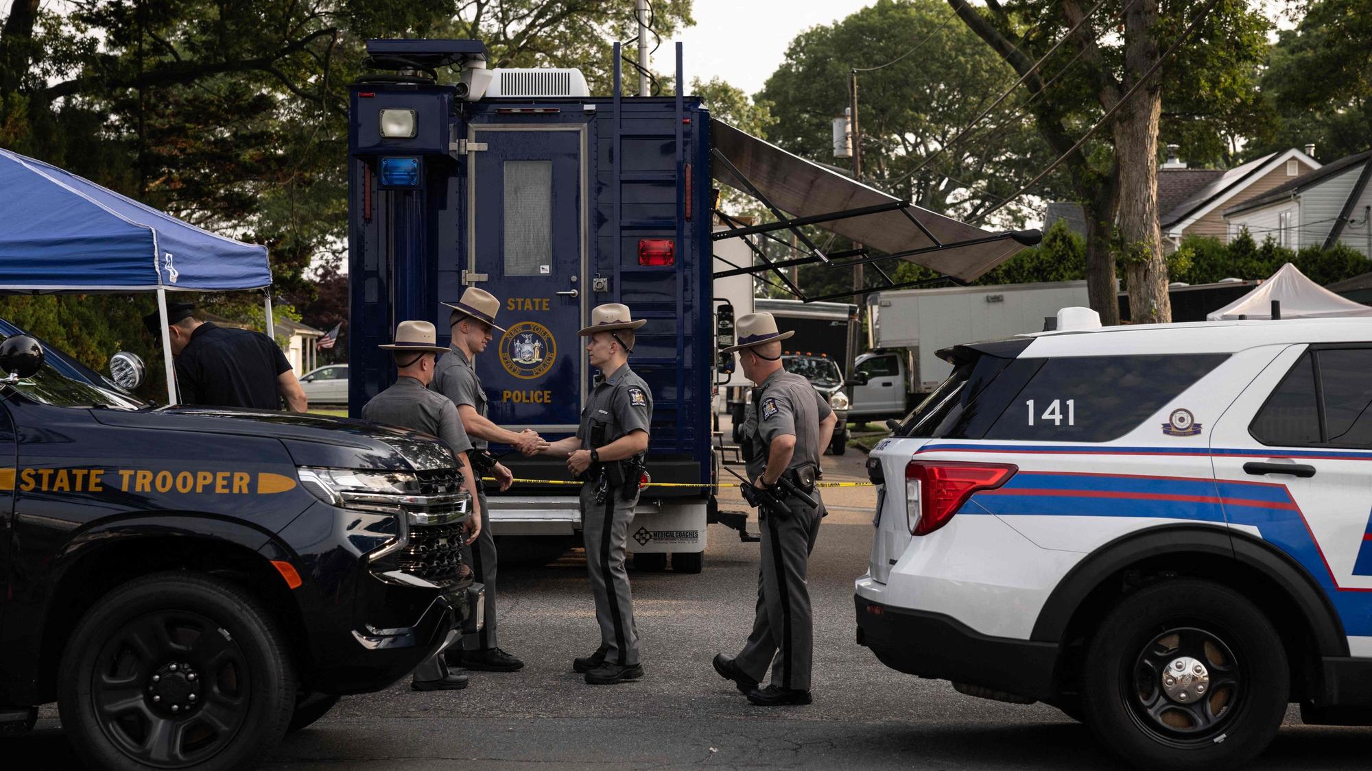 Polizeibeamte des Staates New York stehen Wache, während Ermittler das Haus des Verdächtigen der Gilgo-Beach-Morde, Rex Heuermann, in Massapequa Park, New York, durchsuchen.