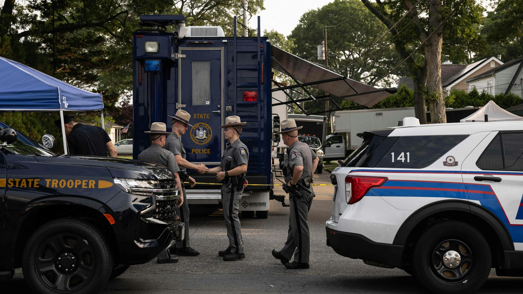 Polizeibeamte des Staates New York stehen Wache, während Ermittler das Haus des Verdächtigen der Gilgo-Beach-Morde, Rex Heuermann, in Massapequa Park, New York, durchsuchen.