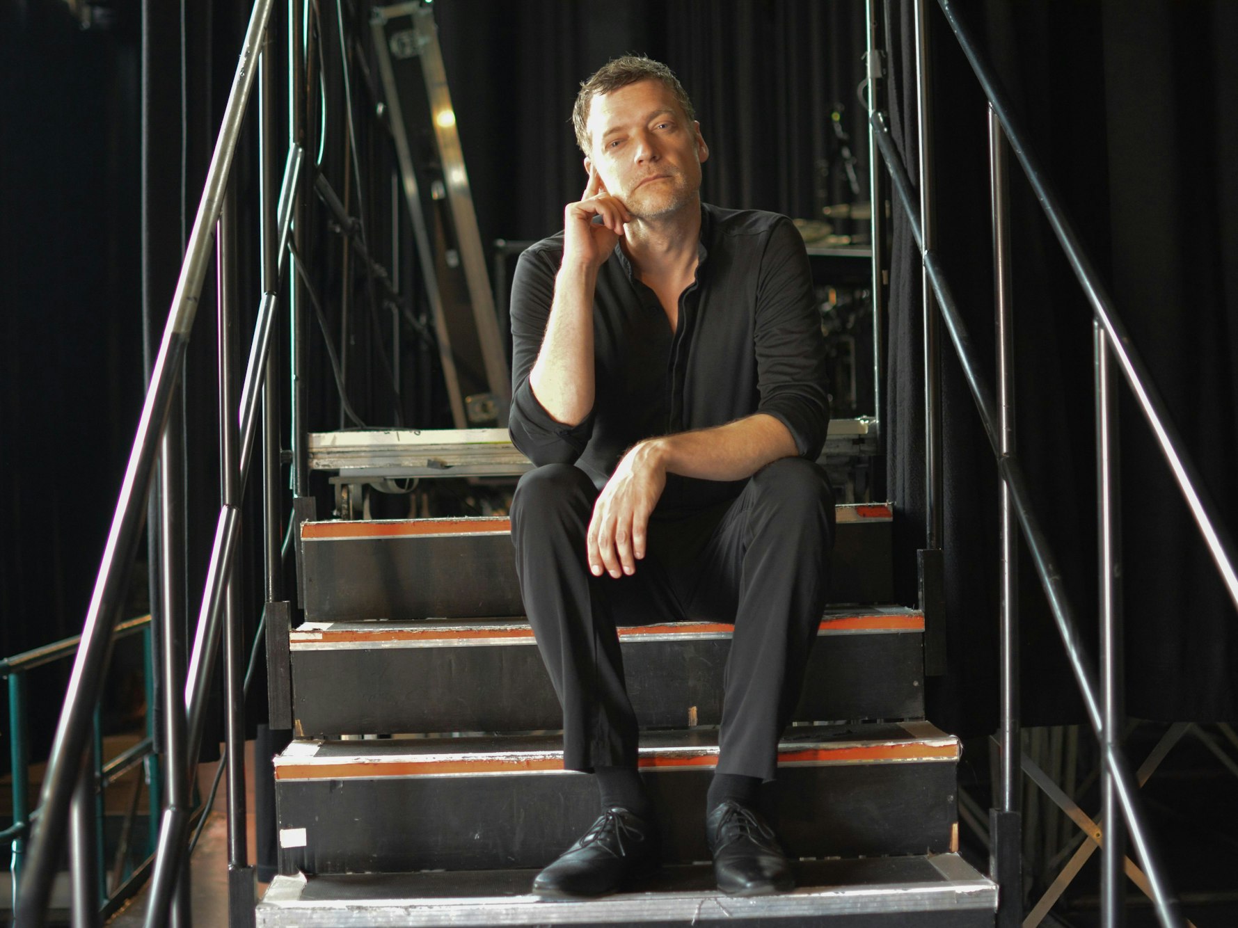 Felix Schönfuss sitzt auf der Treppe zur Bühne im E-Werk.