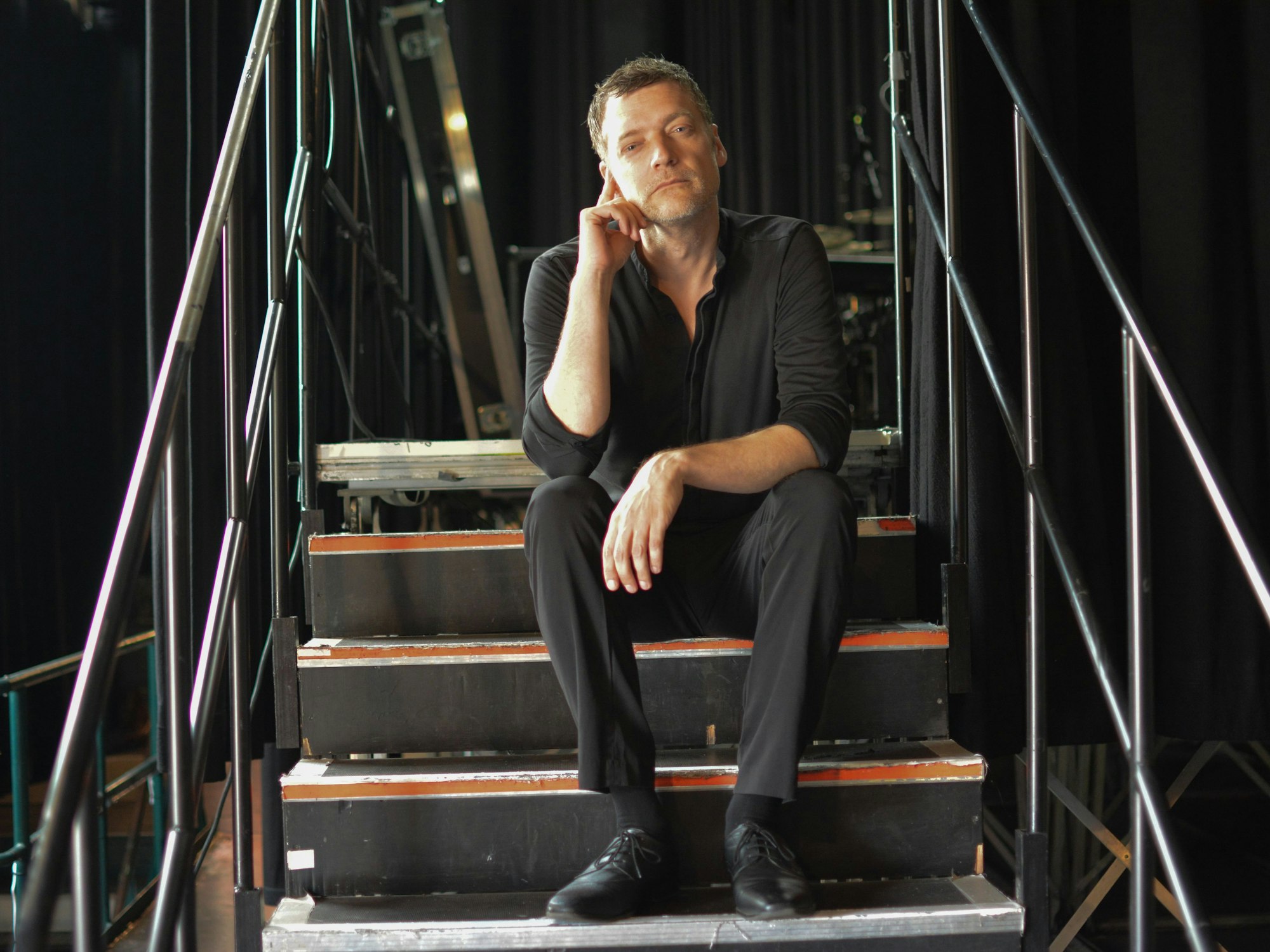 Felix Schönfuss sitzt auf der Treppe zur Bühne im E-Werk.