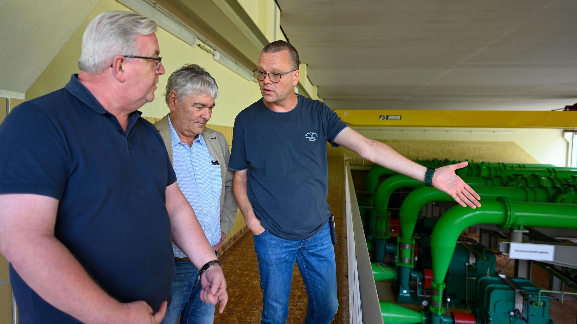 Drei Männer stehen neben Pumpen.