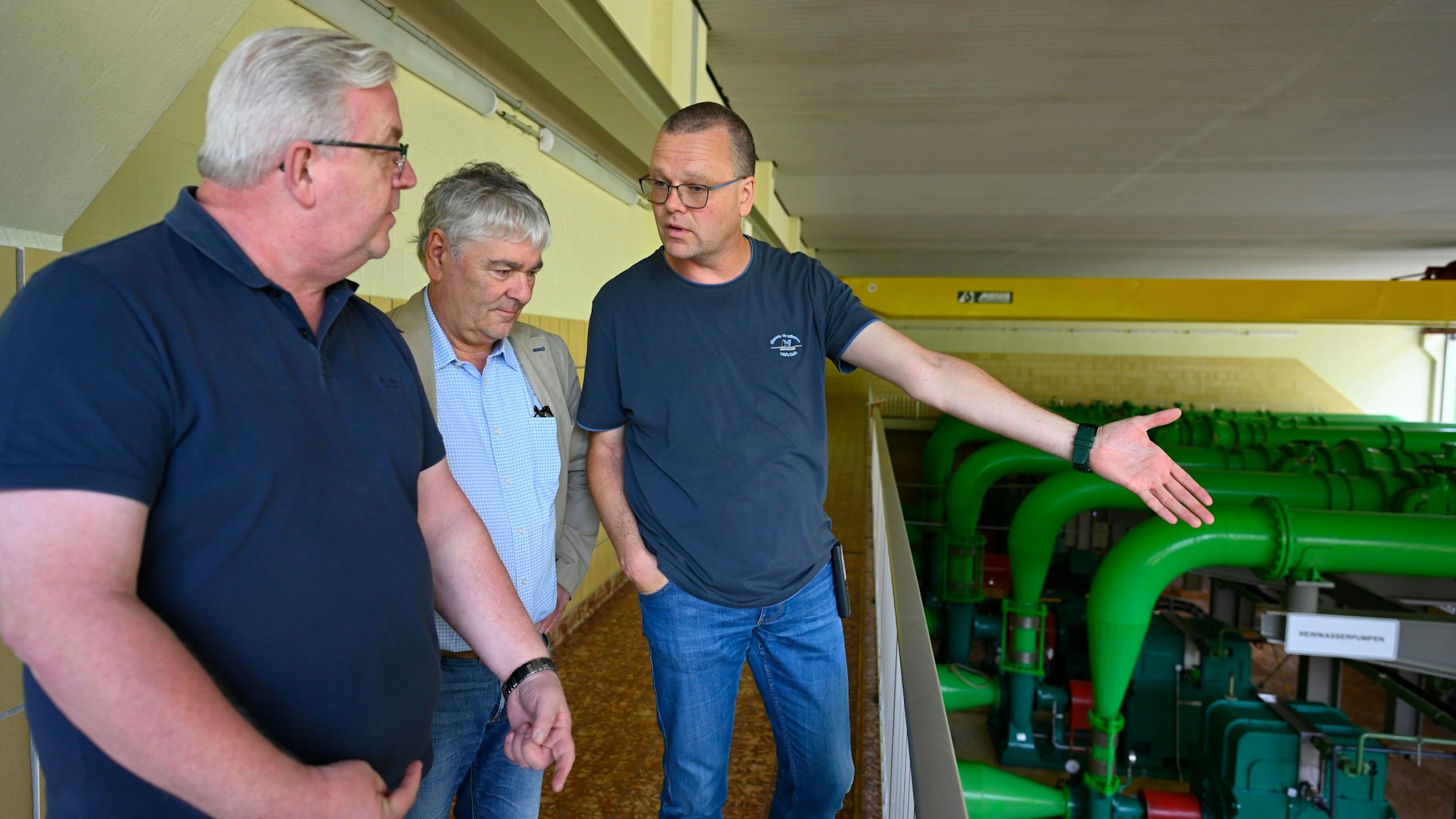 Drei Männer stehen neben Pumpen.