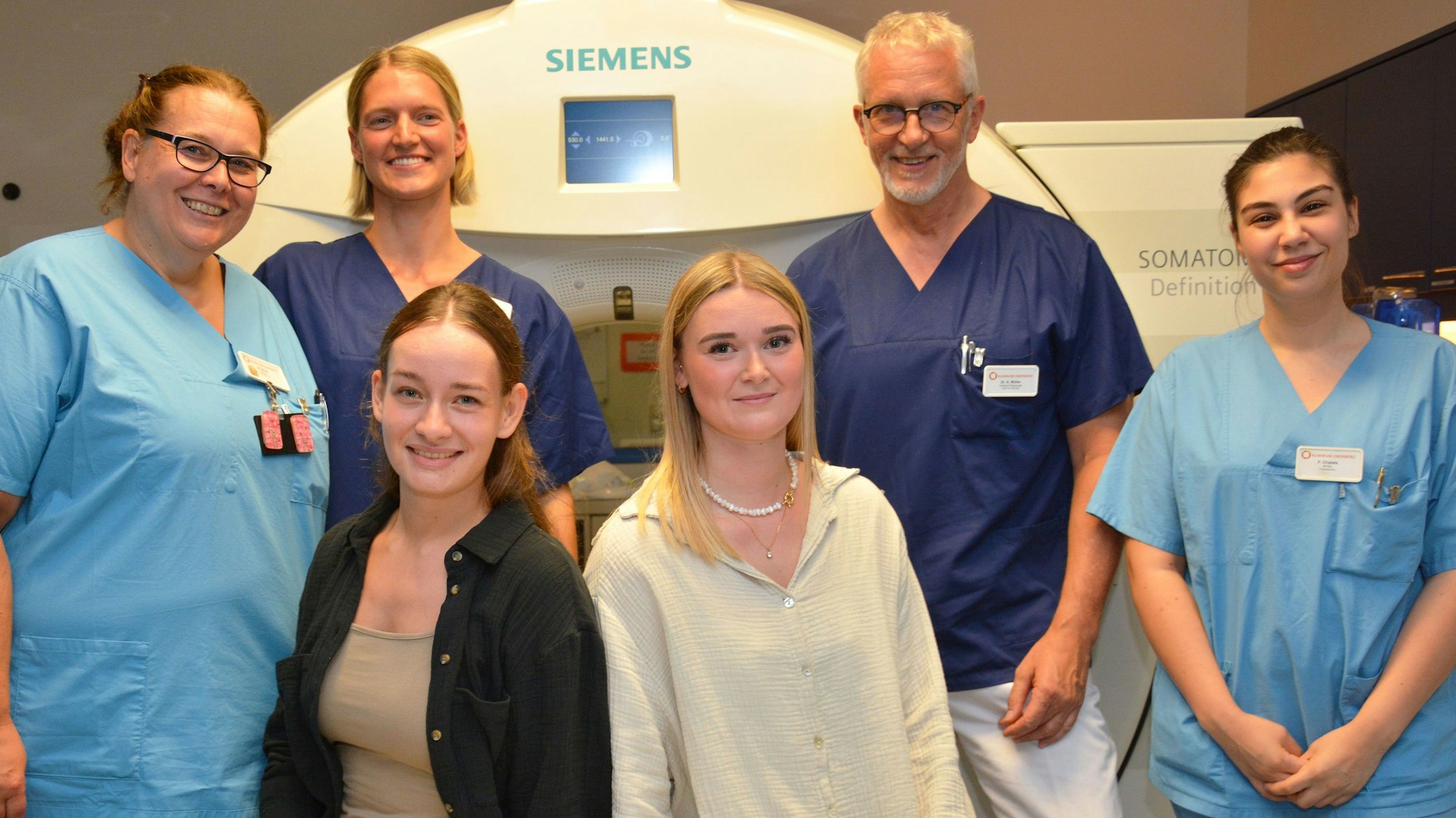 Mehrere Männer und Frauen stehen vor einem MRT-Gerät.