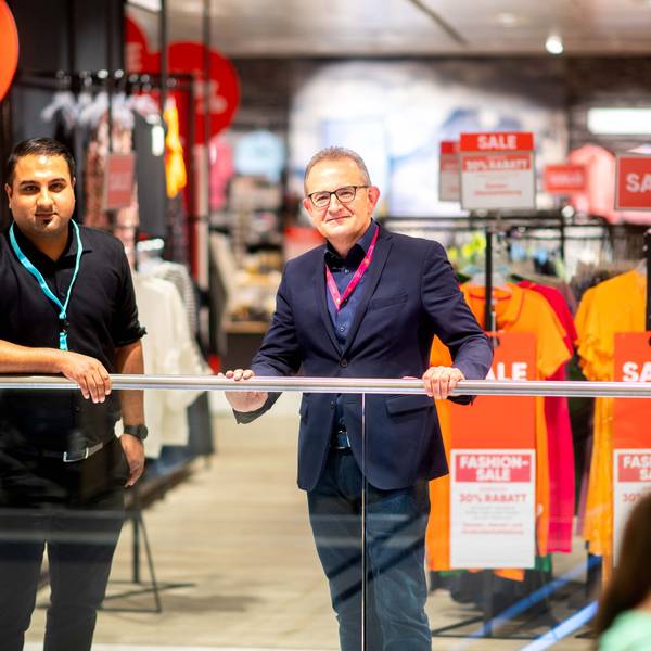 Der neue und der alte Chef der Galeria-Filiale stehen am Geländer.
