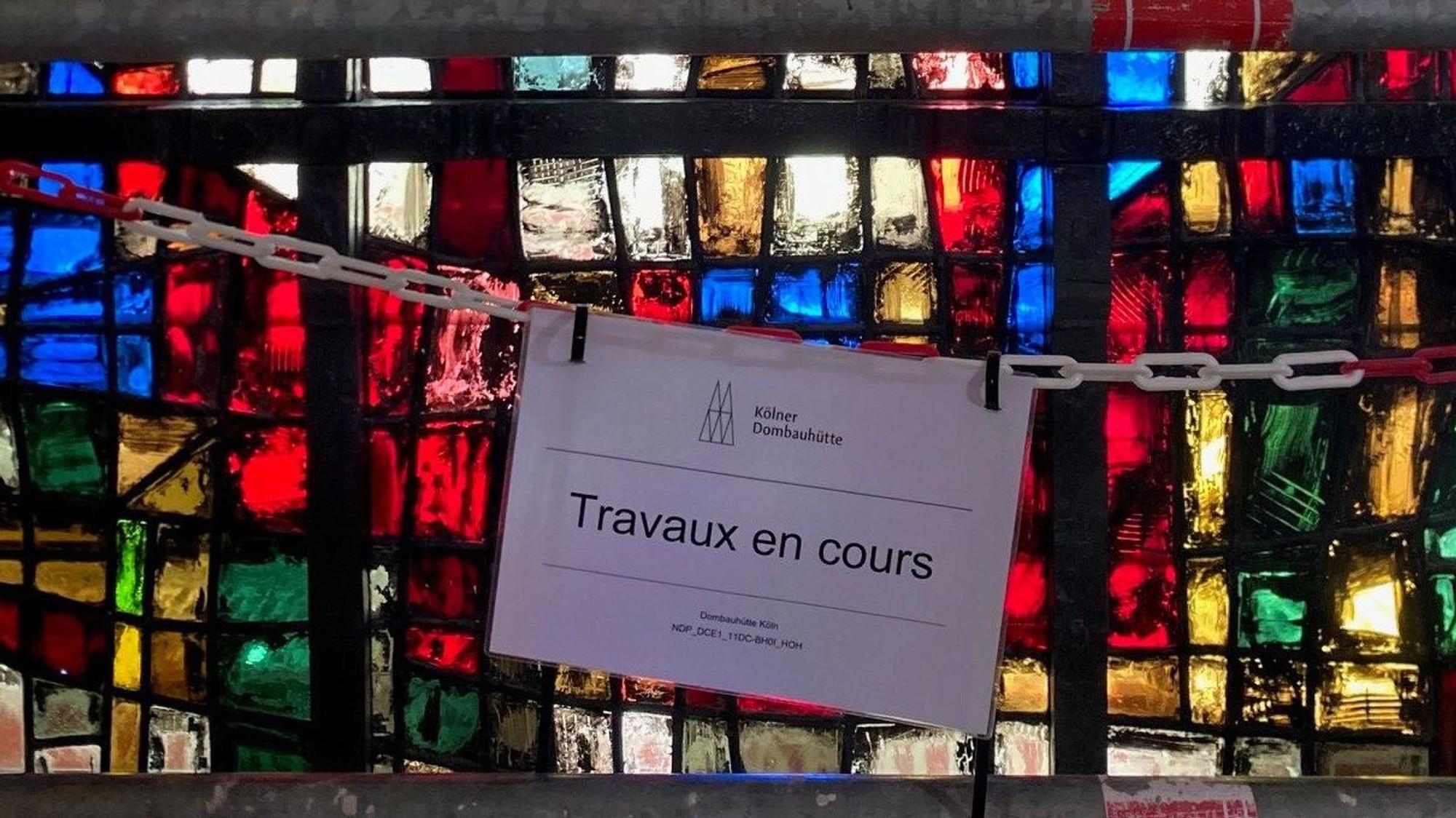 Auf einem Schild in der Pariser Kathedrale Notre-Dame steht „Travaux en cours“ - Bauarbeiten im Gange. Die Kölner Dombauhütte hat vier beim Brand 2019 stark verschmutzte Glasfenster gereinigt, restauriert und jetzt wieder an Ort und Stelle eingebaut.