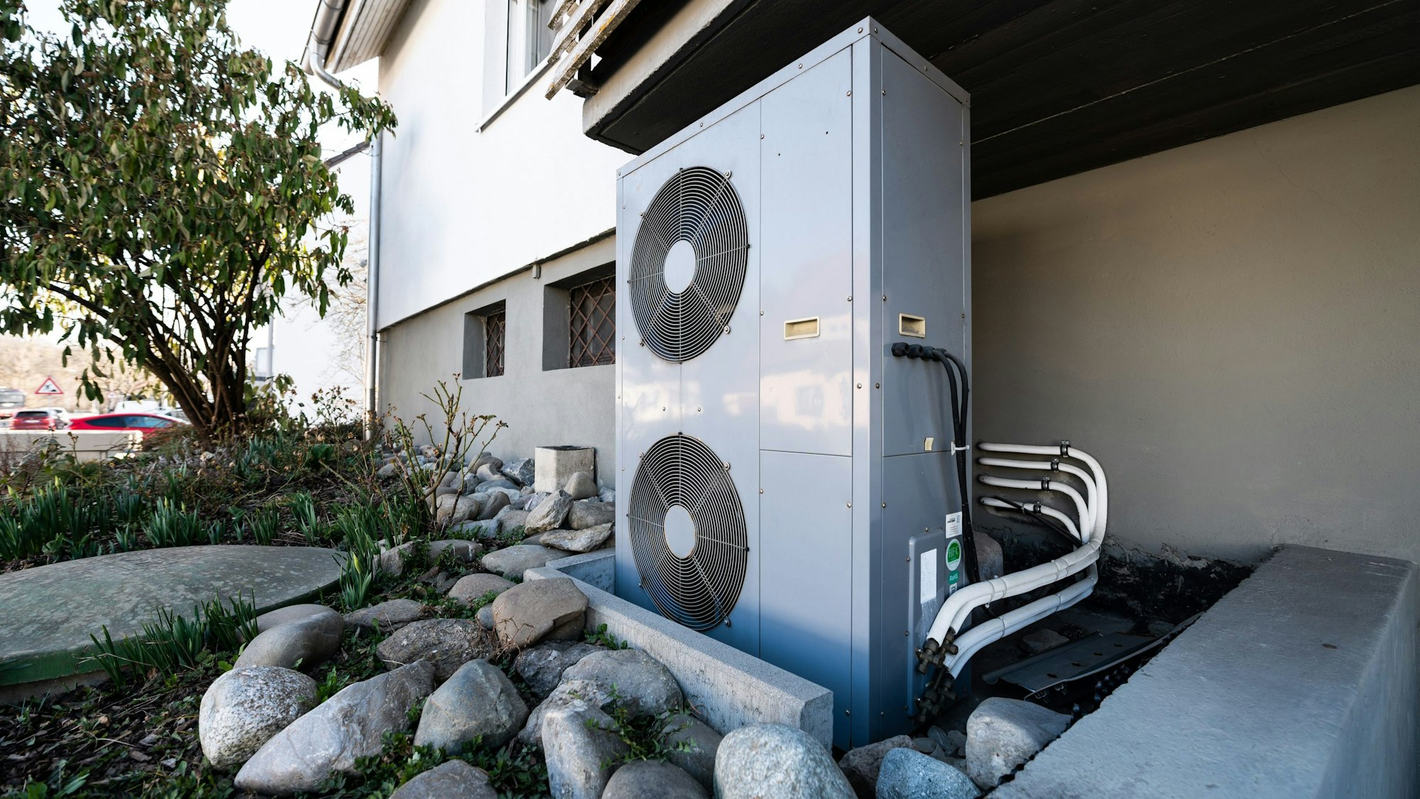 Die Lüftungsanlage einer Wärmepumpe steht vor einem Wohnhaus.