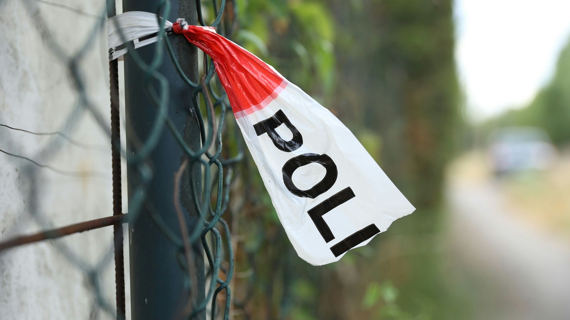 Nahe einem Tatort hängt Polizeiabsperrband an einem Zaun (Symbolbild)