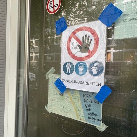 Eingangstür zur Kita Mauritiuswall mit einem Schild, auf dem „Sanierungsarbeiten“ zu lesen ist.