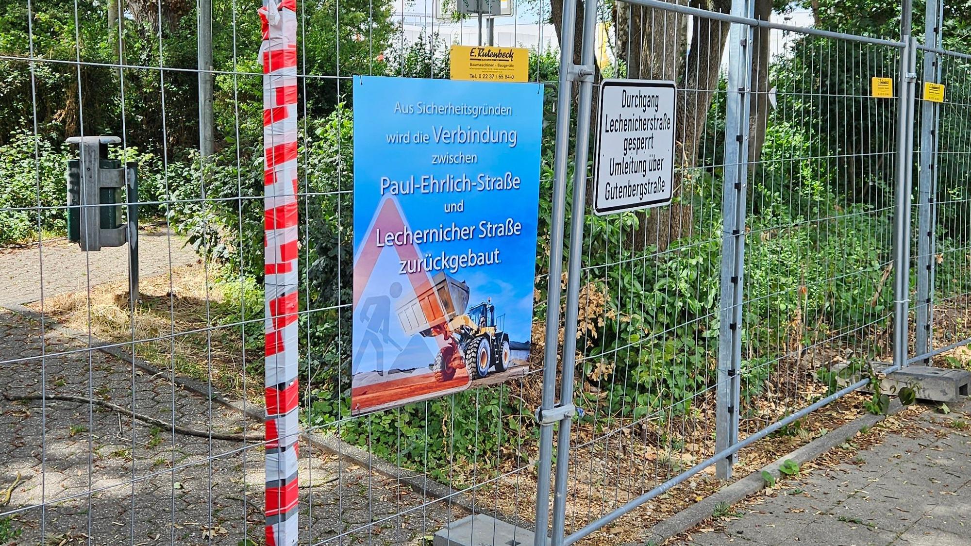 Das Bild zeigt einen Bauzaun vor einem Fußweg.