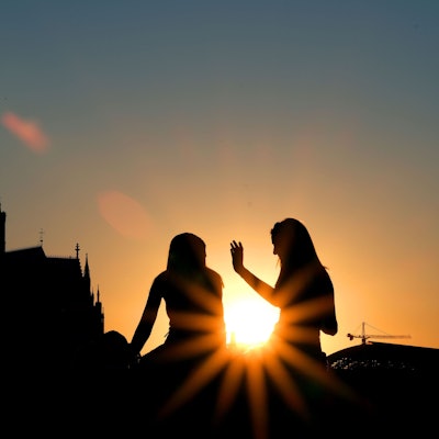 Zwei Frauen sitzen im Sonnenuntergang am Rheinboulevard vor dem Dom. (zu dpa «Drei Viertel der Deutschen finden Kirchensteuer nicht zeitgemäß»)