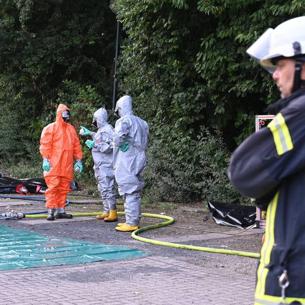 Das Foto zeigt Feuerwehrleute in Schutzanzügen vor der Erftlagune.