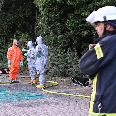 Das Foto zeigt Feuerwehrleute in Schutzanzügen vor der Erftlagune.