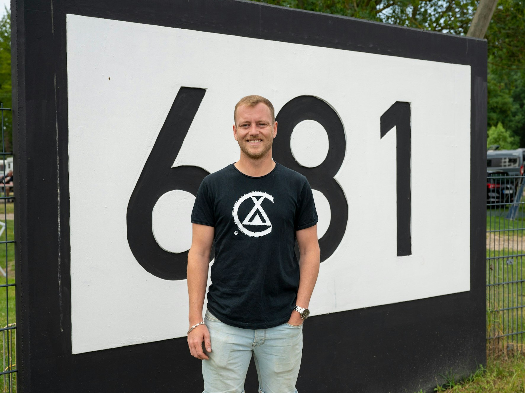 Benedikt Berger steht an der Markierung Rheinkilometer 681.