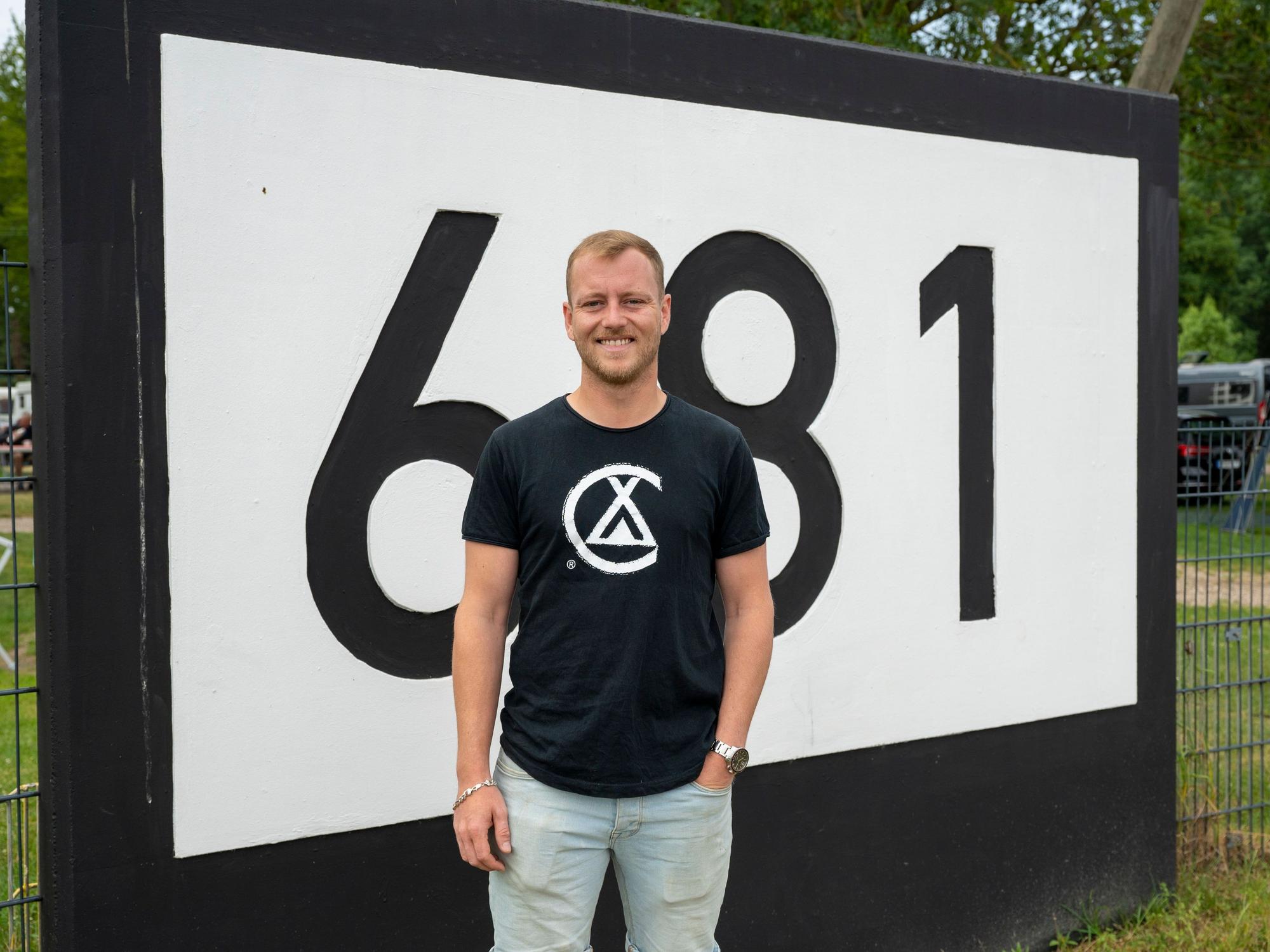 Benedikt Berger steht an der Markierung Rheinkilometer 681.