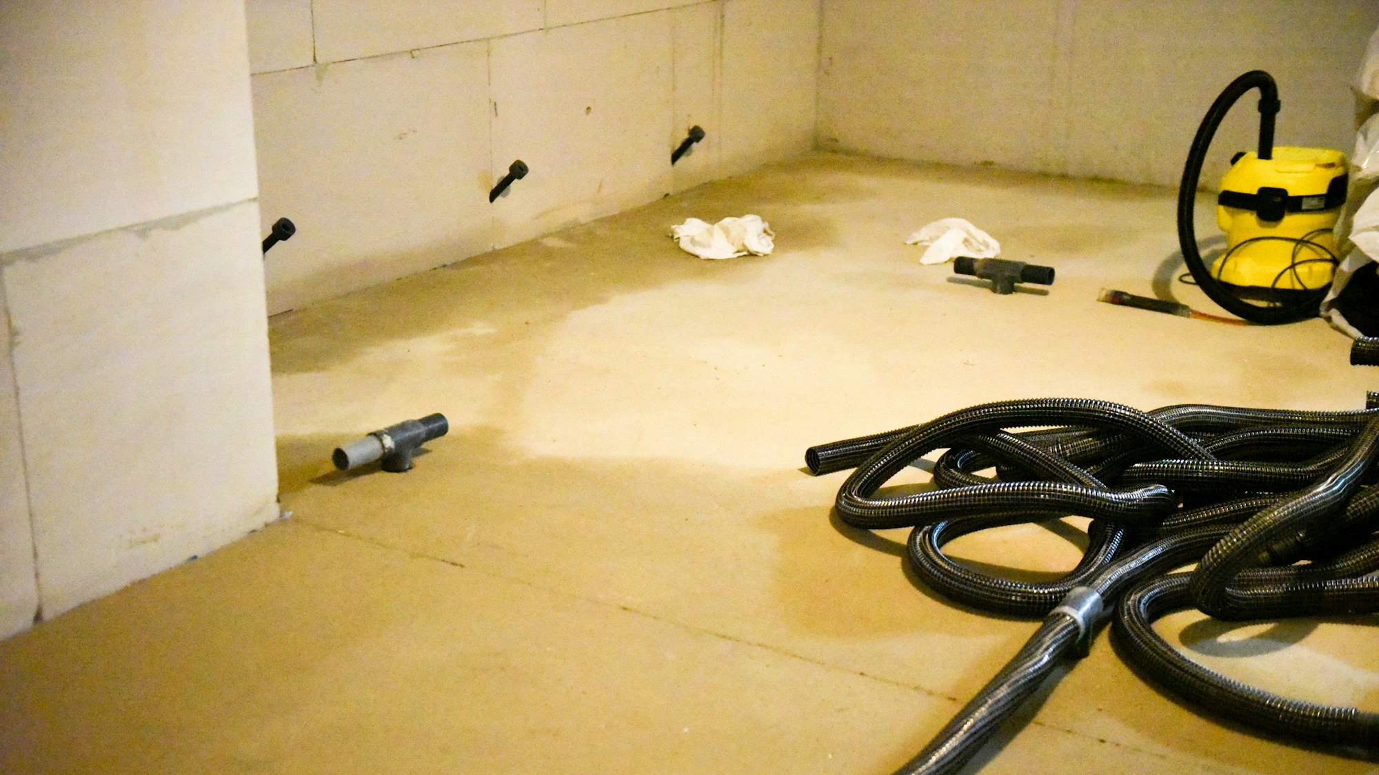 Das Bild zeigt einen Kellerraum, in dem ein Wasserabsauggerät steht.