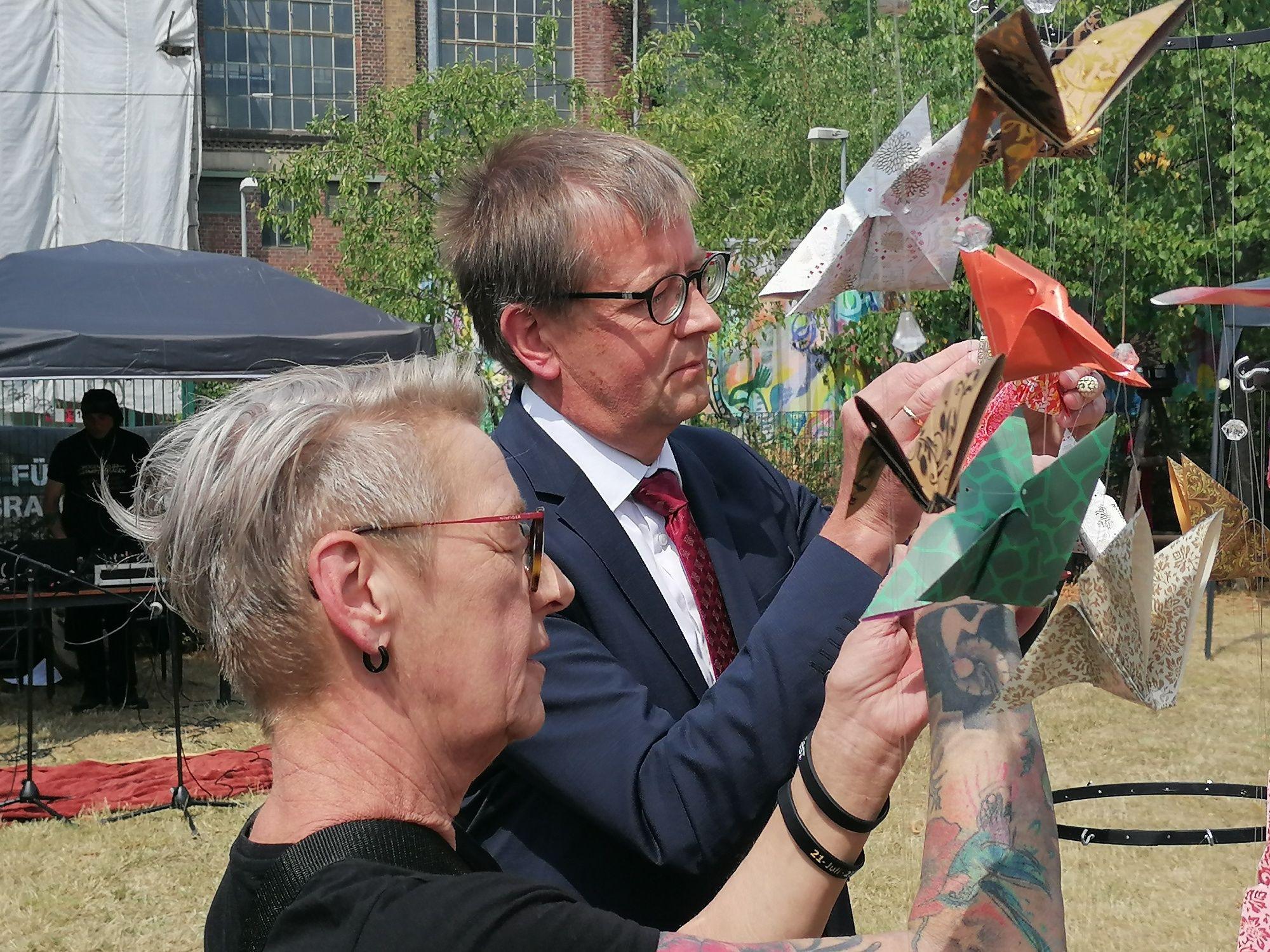 Drogenbeauftragter Burkhard Blienert und Claudia Schieren vom Verein „Vision“ beschriften während der Gedenkveranstaltung Schmetterlinge aus Papier mit Namen von Drogentoten.