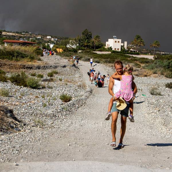 Ein Mann trägt ein Kind, als sie ein Gebiet verlassen, in dem ein Waldbrand auf der griechischen Insel Rhodos wütet. Ein großes Waldfeuer hat die Behörden gezwungen, die Evakuierung von vier Orten anzuordnen, darunter zwei Badeorte.