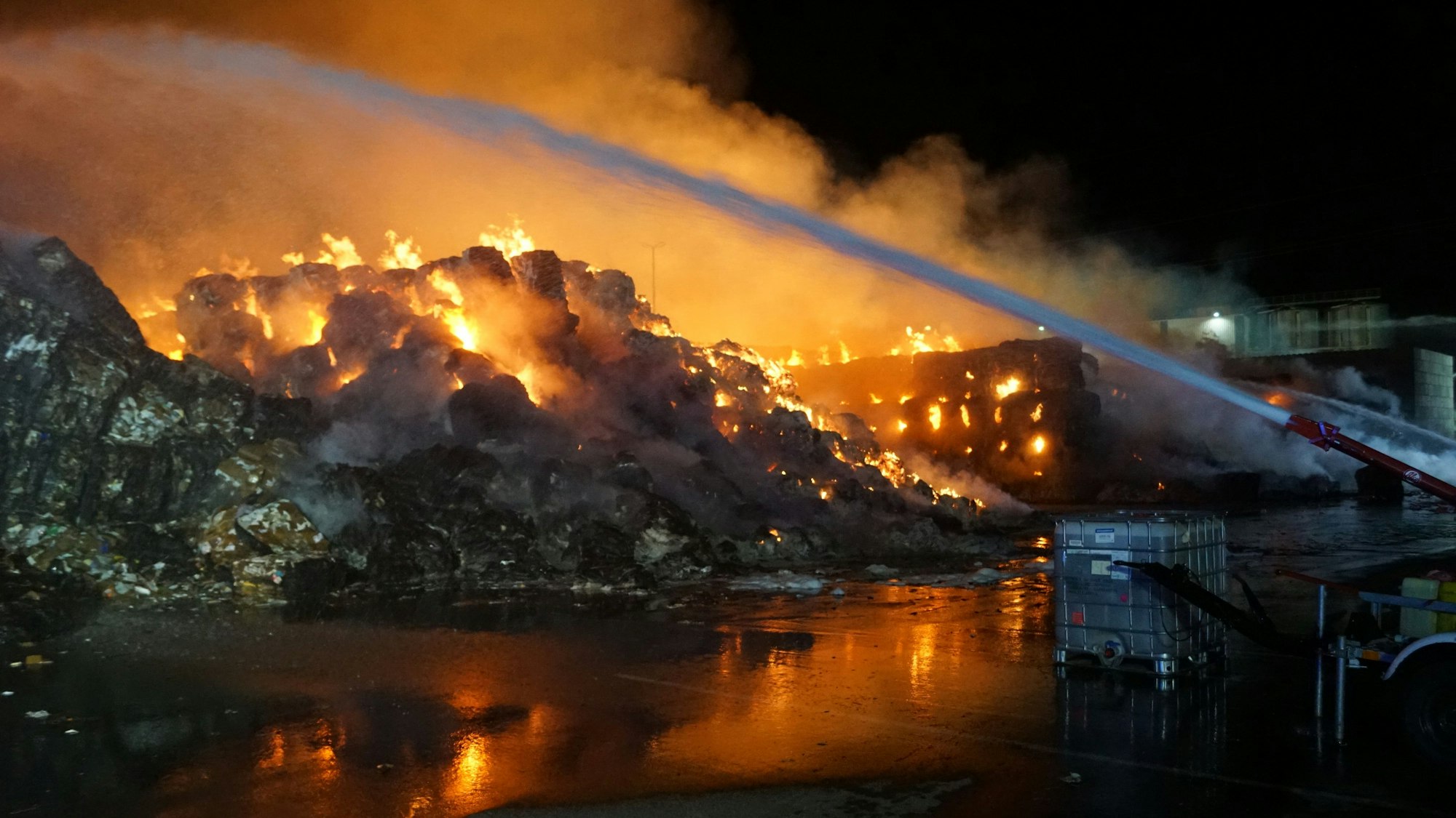 Das Bild zeigt brennende Papierballen in der Nacht.