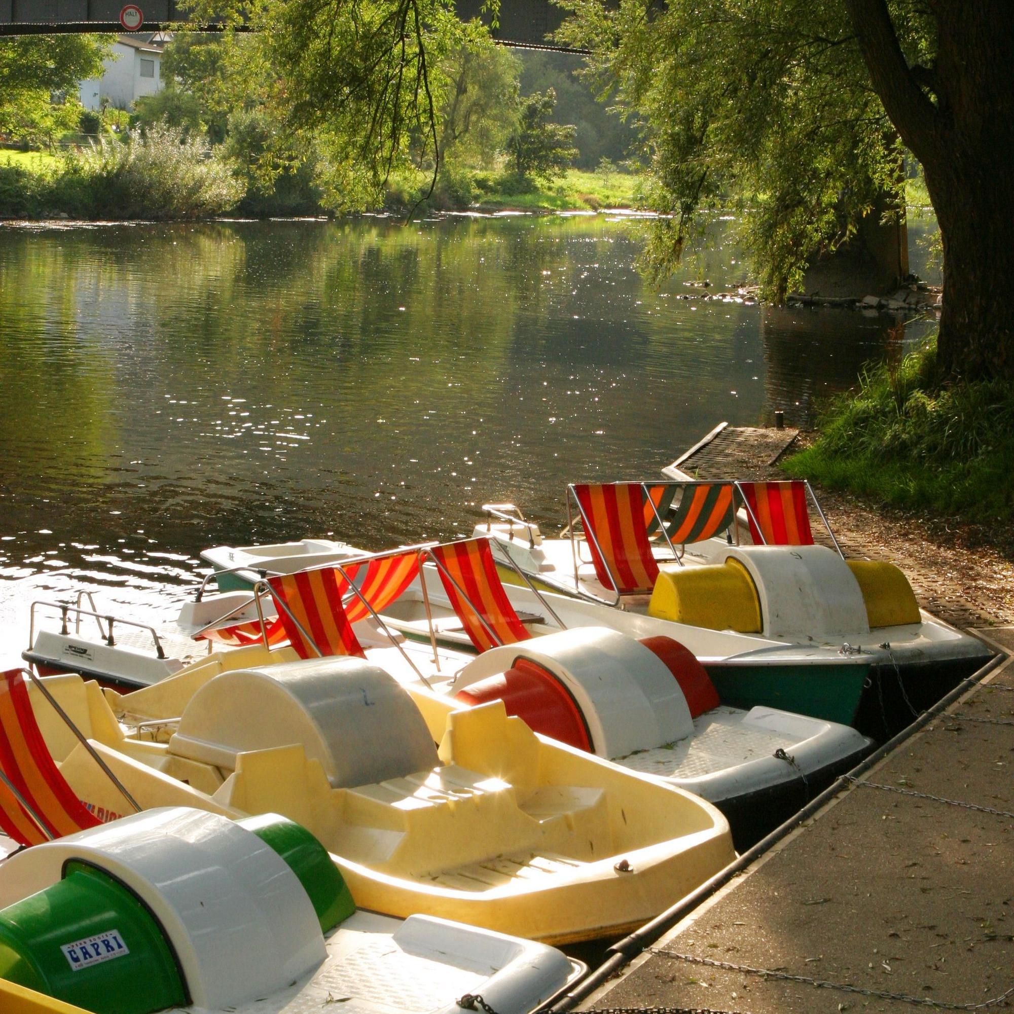 Tretboote liegen in der Sonne an einem Steg.