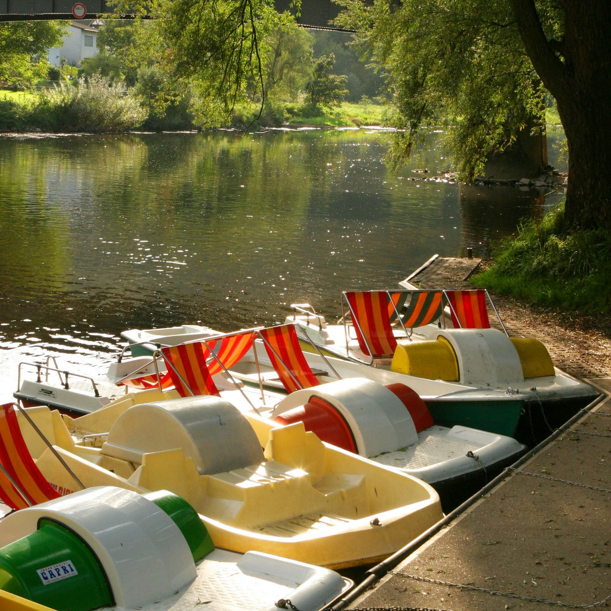 Tretboote liegen in der Sonne an einem Steg.