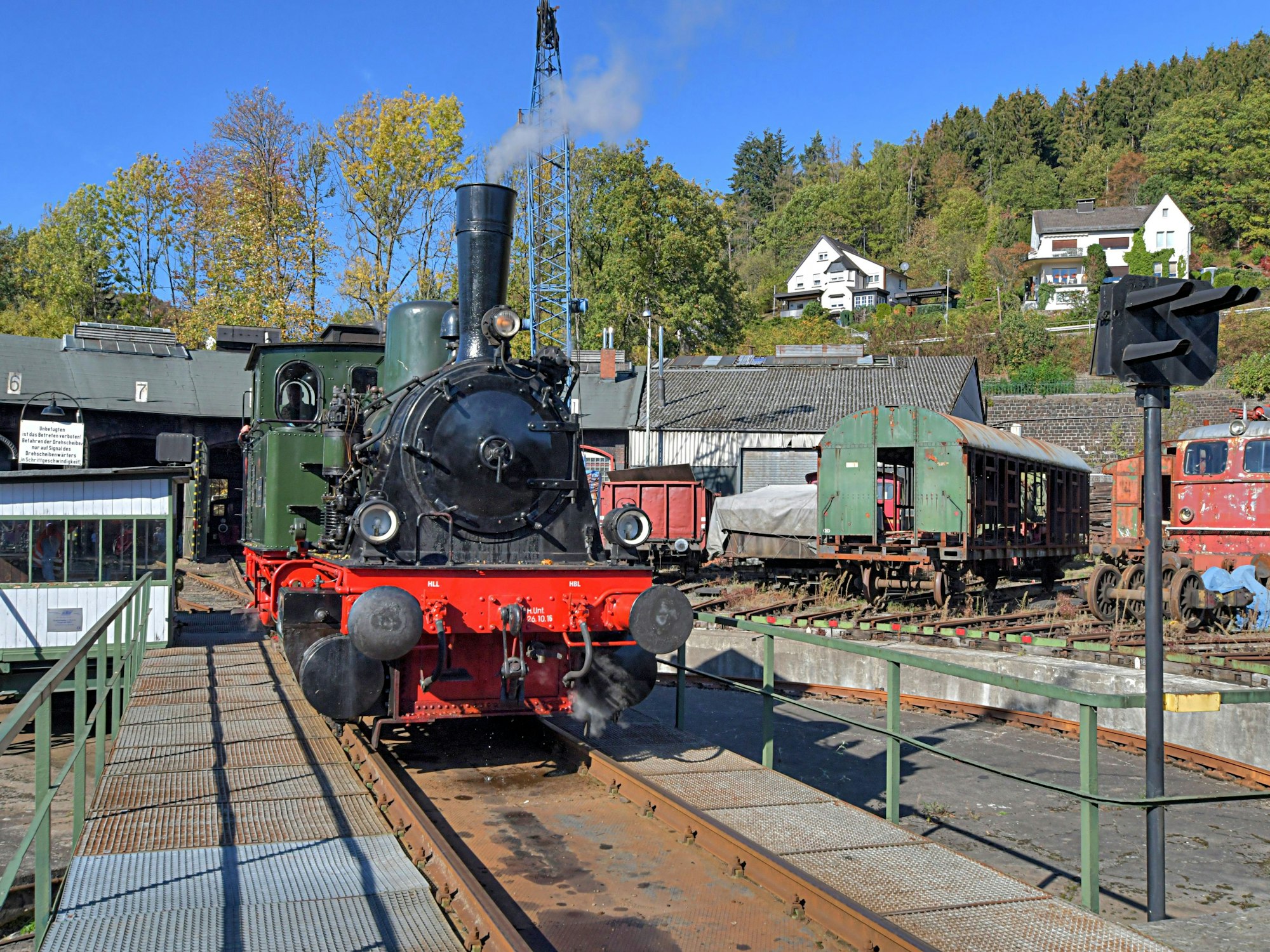 Eine Dampflokomotive steht auf einer Drehscheibe vor einem Lokschuppen.