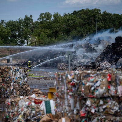 Das Bild zeigt Altpapierballen, die auf dem Gelände von Smurfit Kappa in Brand geraten sind. Die Feuerwehr löscht aus zahlreichen Strahlrohren.