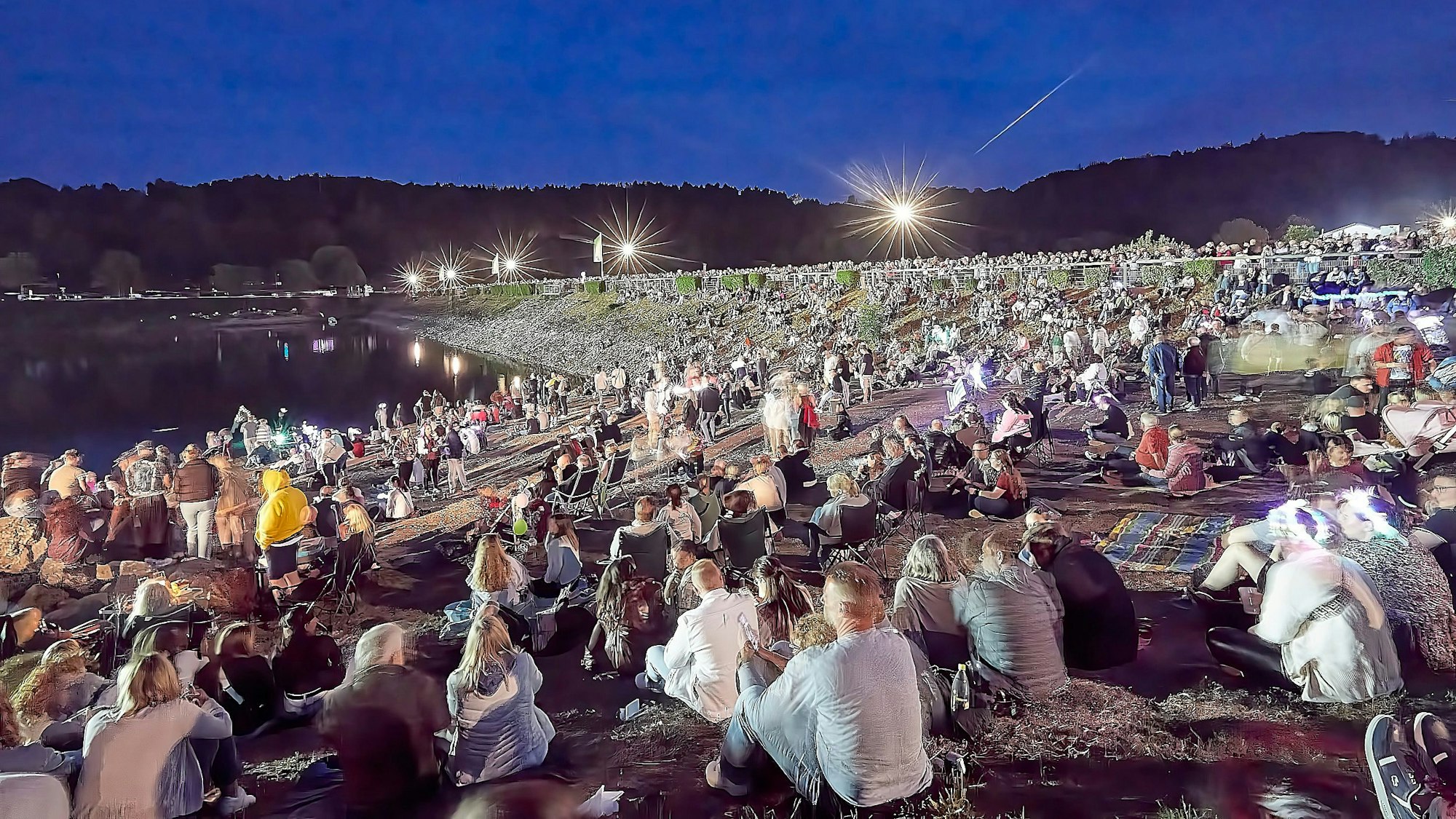 Hunderte Zuschauer erwarten auf dem Damm den Beginn des Feuerwerks.