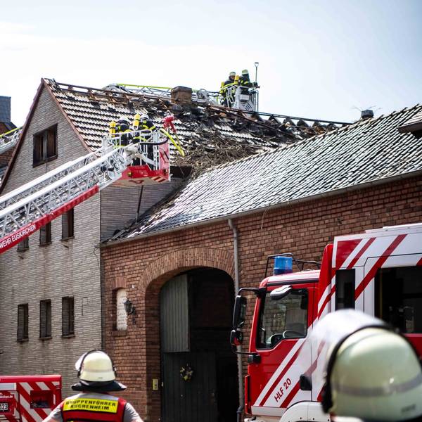 Auf dem Bild ist zu sehen, wie das Feuer den Dachstuhl beschädigt hat. Die Feuerwehr begutachtet mithilfe von zwei Drehleitern den Schaden.