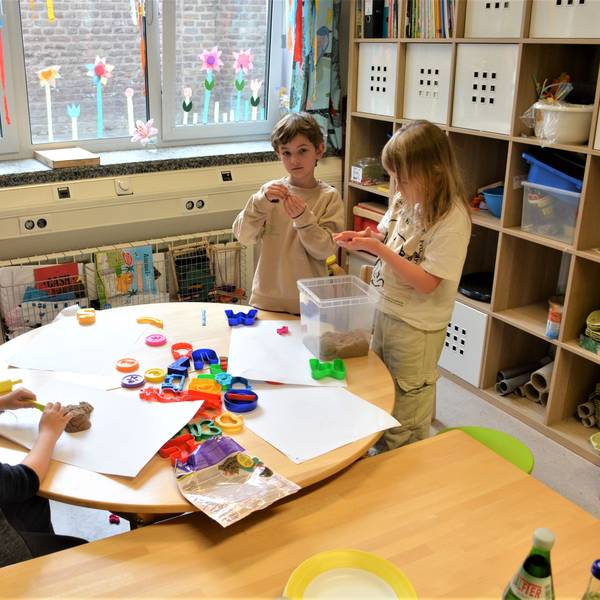 Drei Kinder stehen an einem Tisch und basteln.