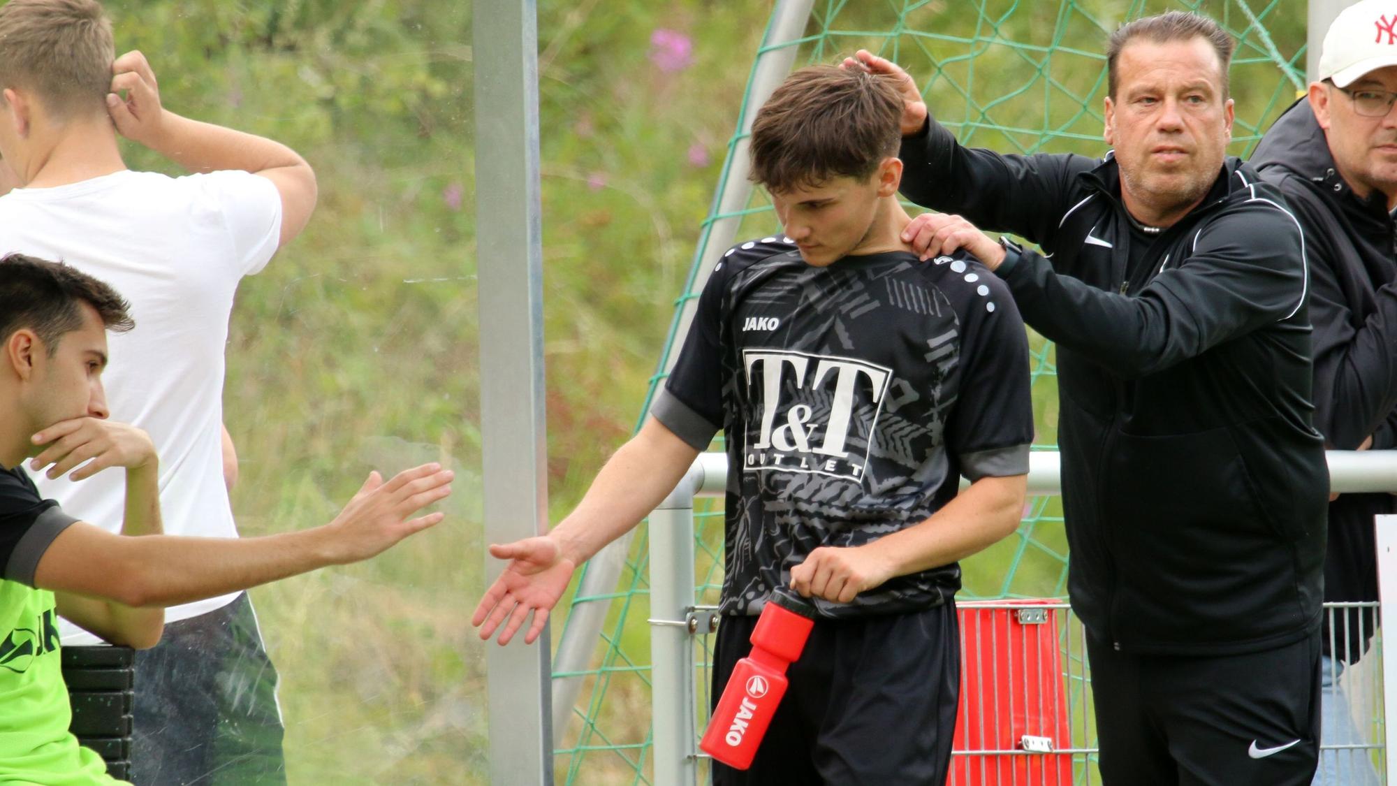Trainer Stephan Reimer ist rechts zu sehen, in der Mitte und links zwei Jugendspieler, die sich abklatschen.