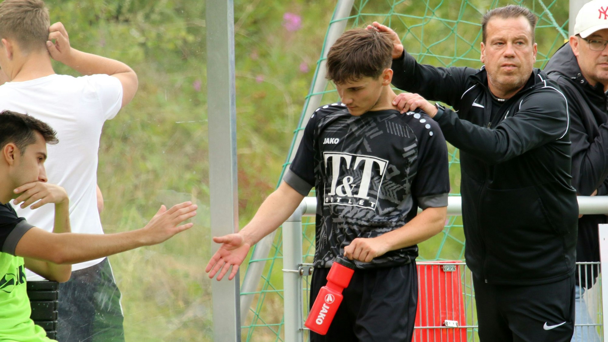 Trainer Stephan Reimer ist rechts zu sehen, in der Mitte und links zwei Jugendspieler, die sich abklatschen.
