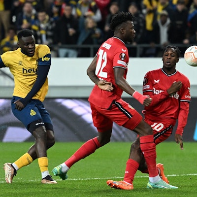 Victor Boniface (l. ) schießt aufs Tor gegen Leverkusens Edmond Tapsoba und Jeremie Frimpong.