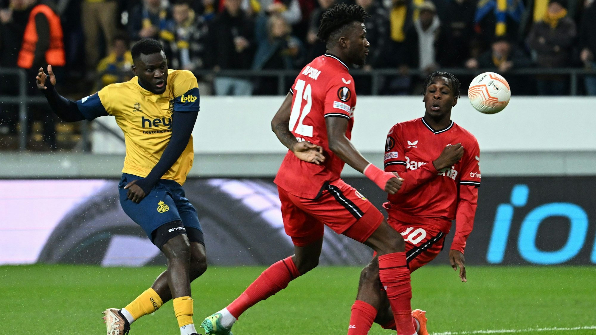 Victor Boniface (l. ) schießt aufs Tor gegen Leverkusens Edmond Tapsoba und Jeremie Frimpong.