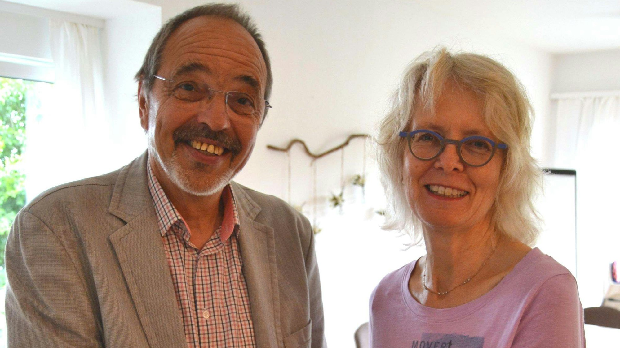 Ein Mann und eine Frau stehen nebeneinander. Sie übergibt ihm einen Schlüssel.