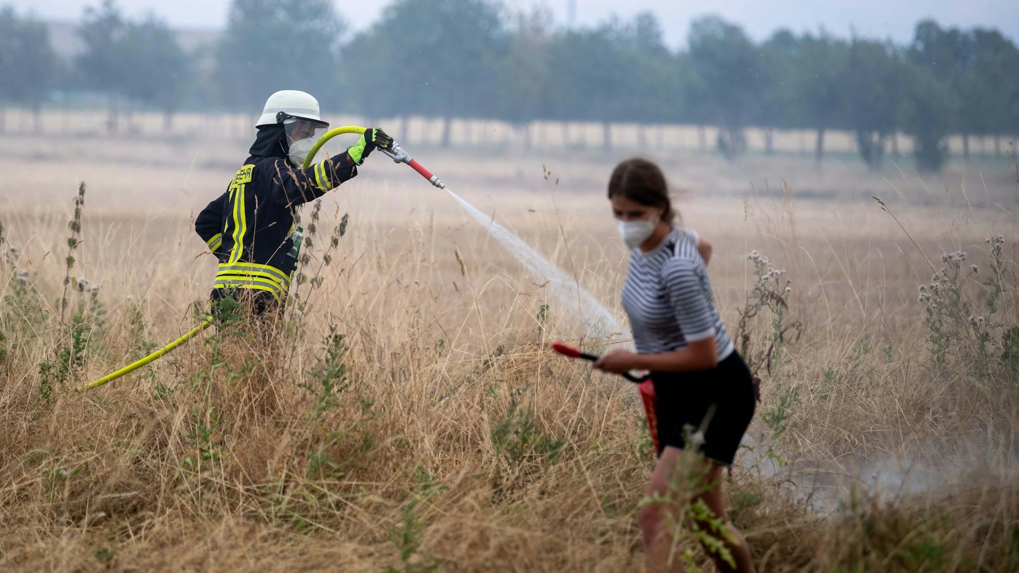 Ein Feuerwehrmann löscht einen Kleinbrand auf einem Feld.