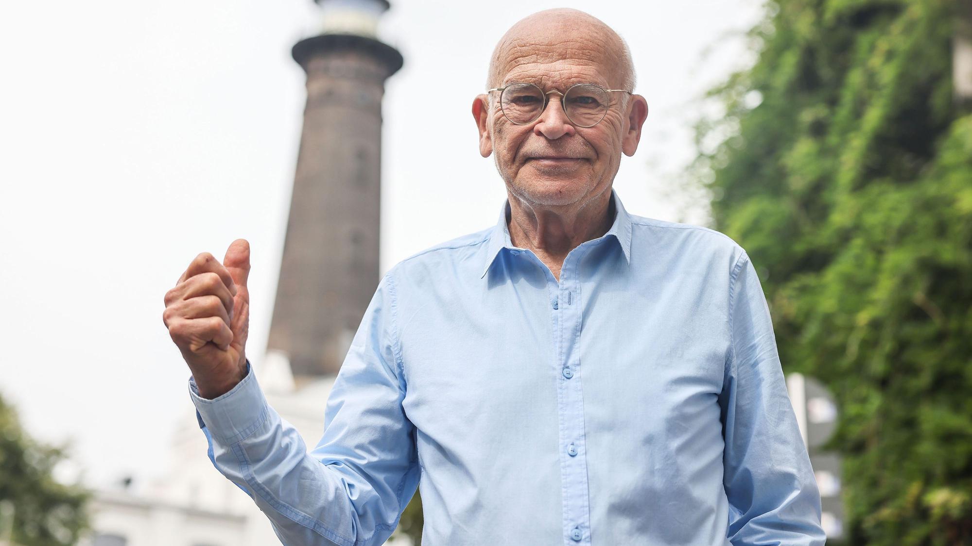 PRODUKTION - 21.07.2023, Nordrhein-Westfalen, Köln: Günter Wallraff, Schriftsteller und Bürger von Ehrenfeld, steht vor dem dem Leuchtturm. Im Kölner Stadtteil Ehrenfeld steht Nordrhein-Westfalens einziger Leuchtturm. Einen Nutzen hat er nicht. Er ist einfach nur da - und wird vielleicht gerade deshalb so geliebt. Der bekannteste Ehrenfelder macht sich jetzt für eine Belebung stark. (Zu dpa/lnw: ·Der Leuchtturm von Köln-Ehrenfeld - Ohne Sinn und doch geliebt·) Foto: Oliver Berg/dpa +++ dpa-Bildfunk +++