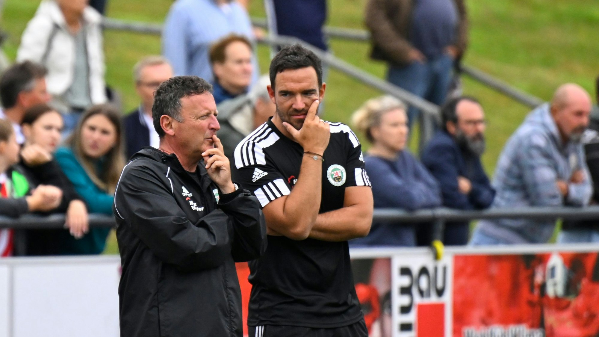 Szene mit zwei Fußballtrainern am Spielfeldrand.