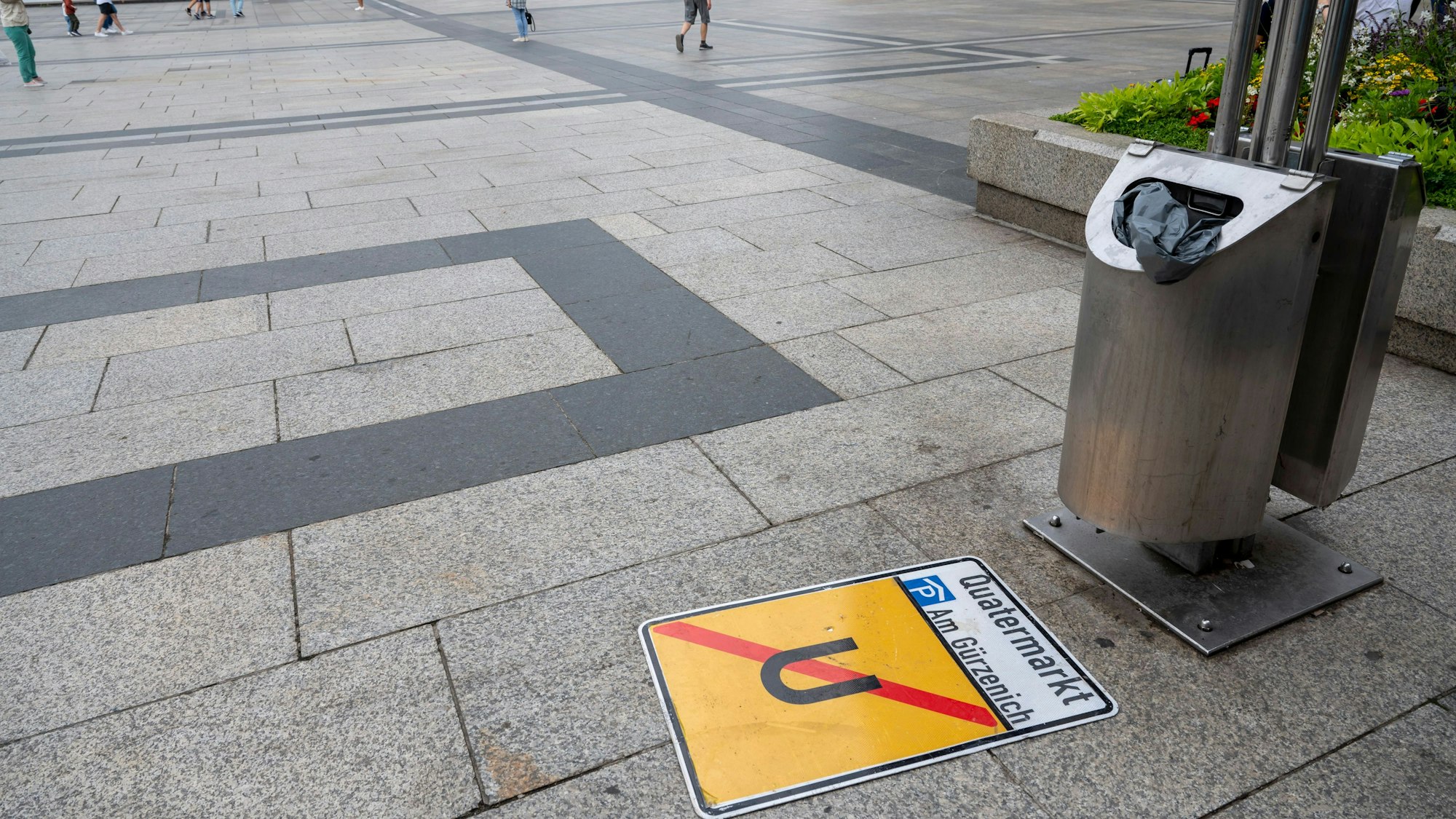 Ein heruntergefallenes Umleitungsschild liegt vor einem Mülleimer auf dem Roncalliplatz.