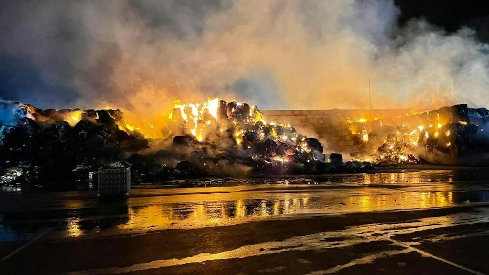 Aus Quadern schlagen hohe Flammen, Rauch steigt in den Nachthimmel auf.