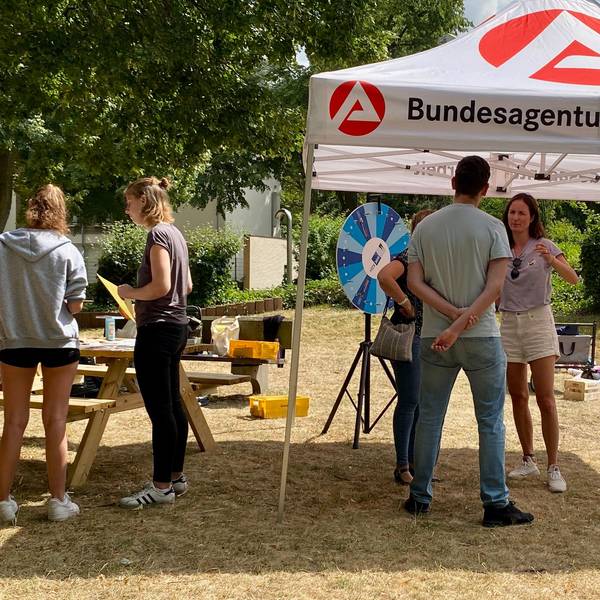 Auf dem Foto ist der Infostand der Arbeitsagentur zu sehen. Berater sprechen mit intereessierten Jugendlichen.