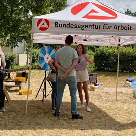 Auf dem Foto ist der Infostand der Arbeitsagentur zu sehen. Berater sprechen mit intereessierten Jugendlichen.