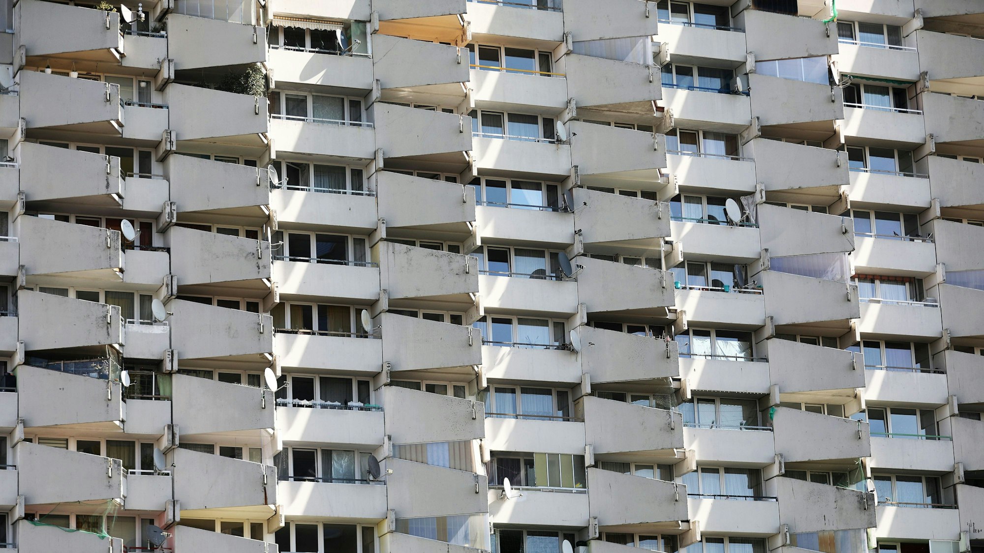 Satellitenschüsseln stehen im Stadtteil Chorweiler auf den Balkonen eines Hochhauses.