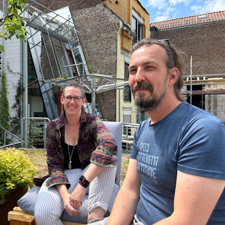 Zwei Leute sitzen auf einer Dachterrasse.